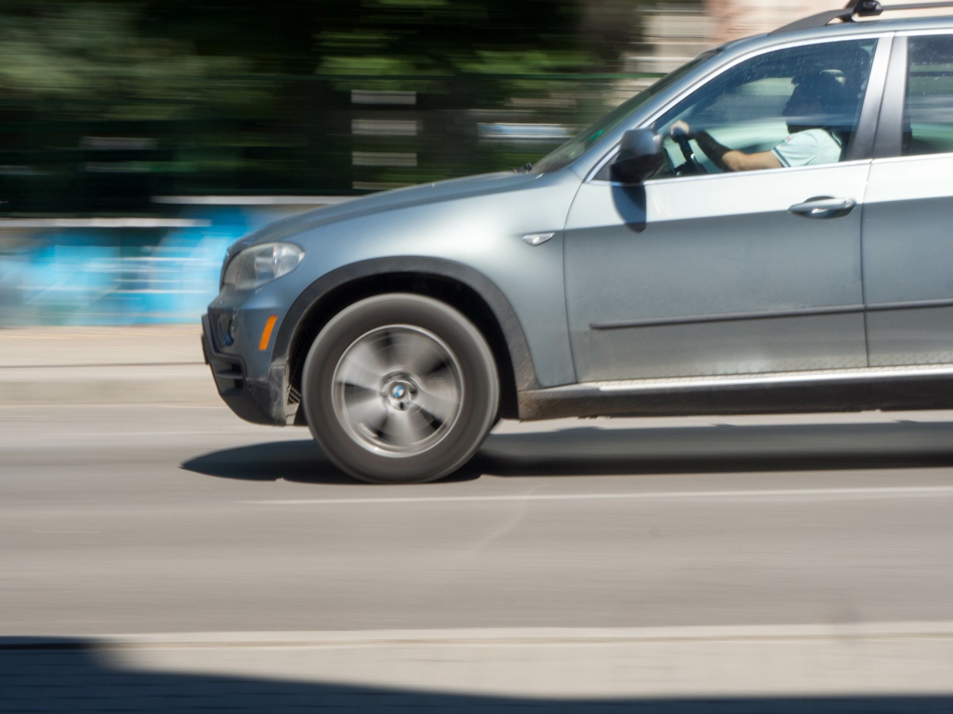 2008 BMW X5 with a driver on his car in streets of the city. Sideview