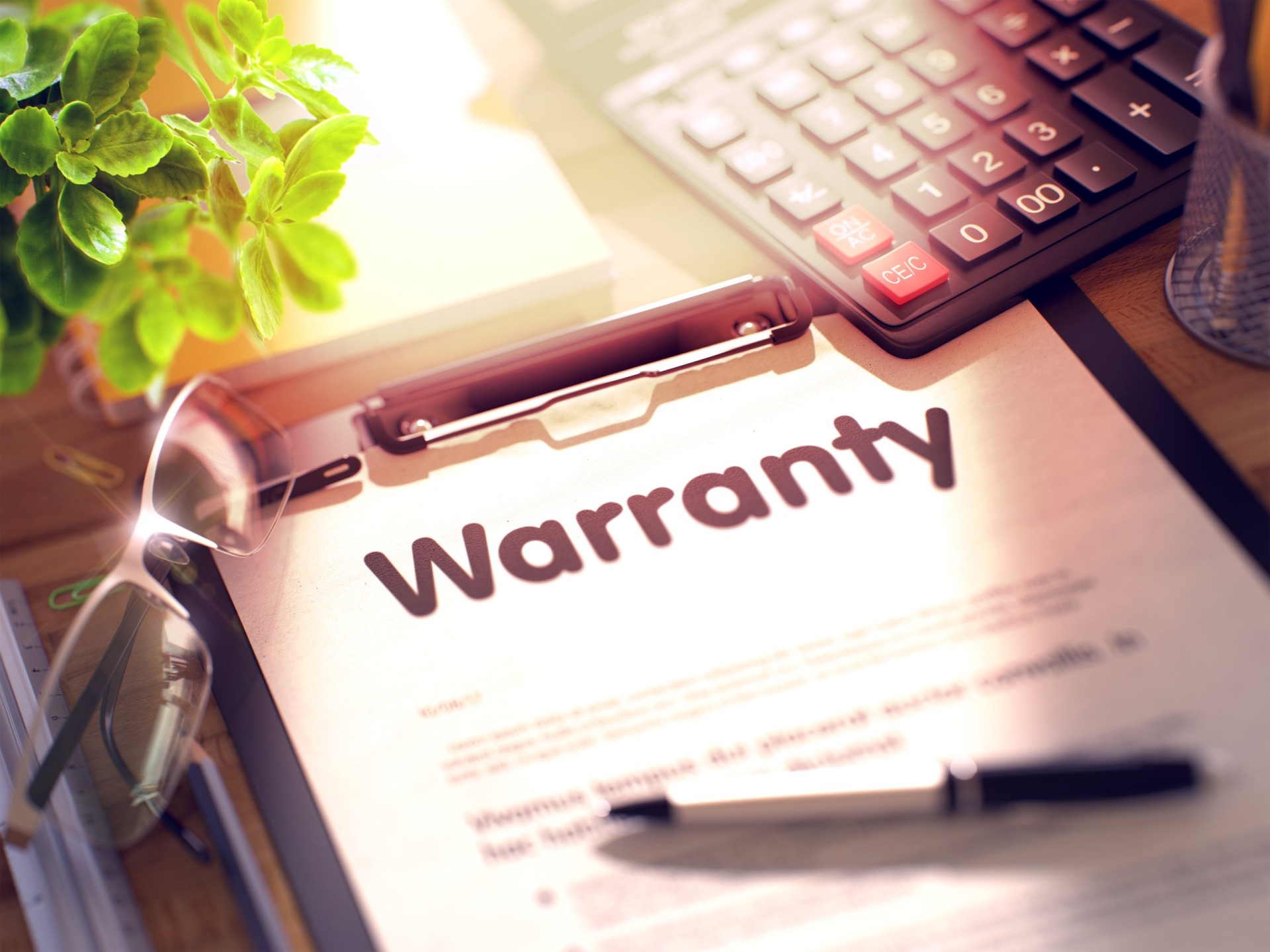 Warranty on Clipboard with Sheet of Paper on Wooden Office Table with Business and Office Supplies Around.