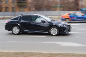 2019 Toyota Camry cruising the streets. Motion image of black shiny car running on the city road