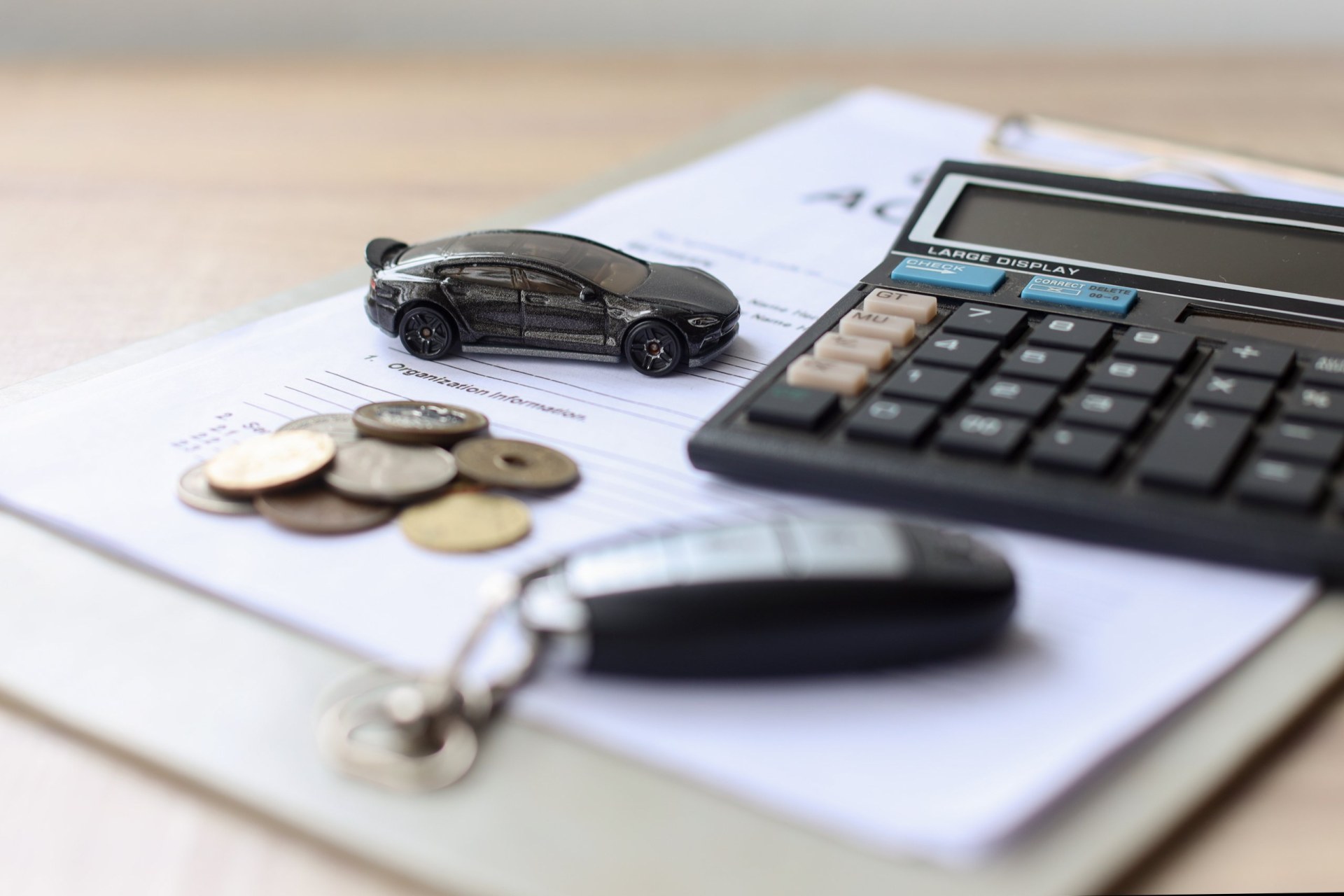 Black car and  key on loan document paper with coins and calculator, saving money and finance for car concept.