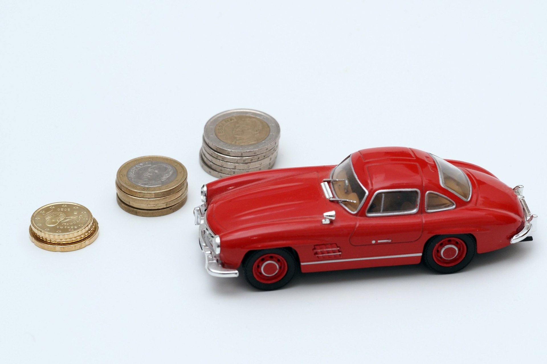 a red car with coins on top of a white table