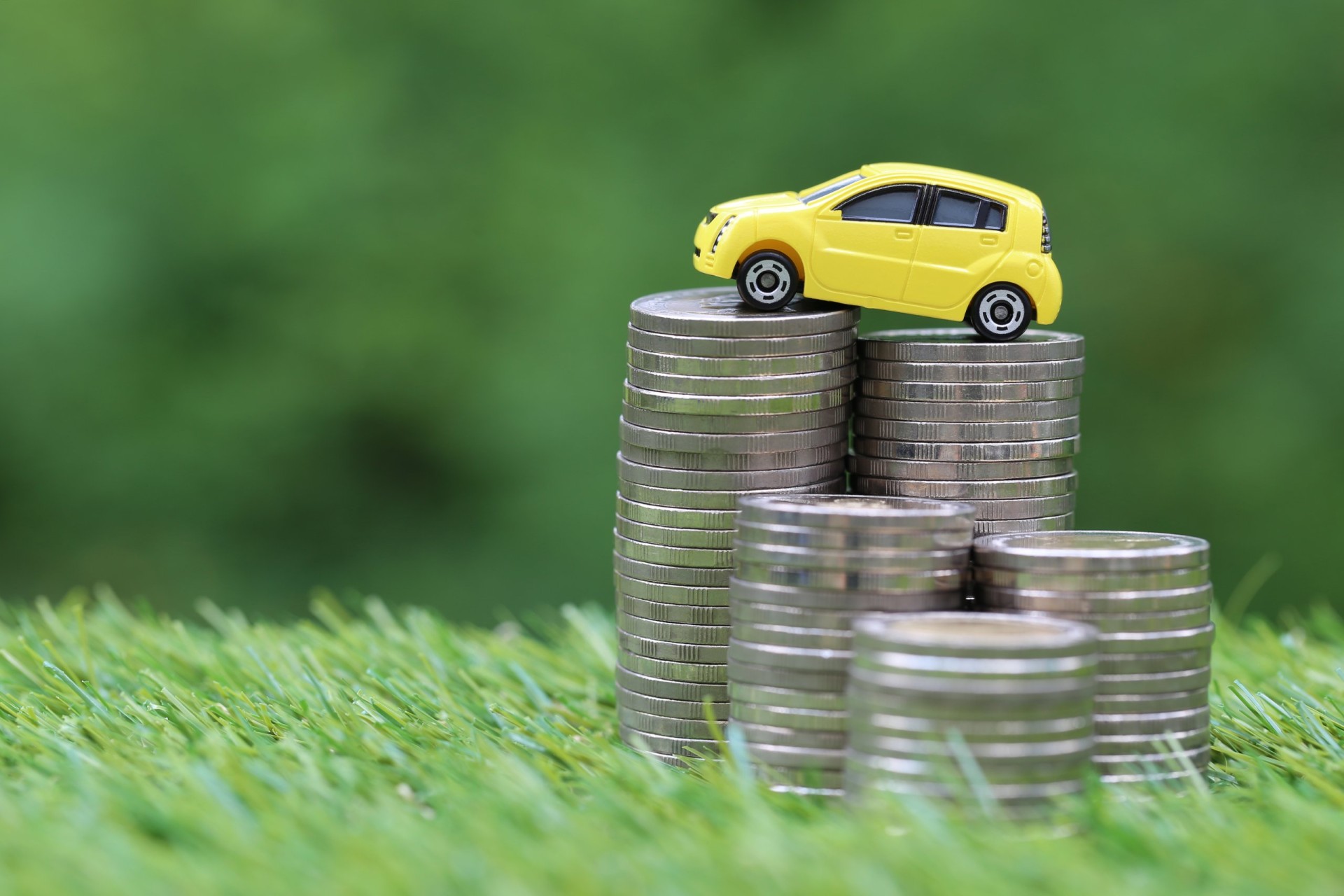 Miniature car model on growing stack of coins money on nature green background, Saving money for car, Finance and car loan, Investment and business concept