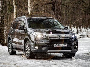 New off-road car Honda Pilot 3 generation black in winter off-road in the forest