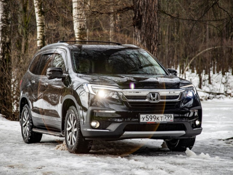 New off-road car Honda Pilot 3 generation black in winter off-road in the forest