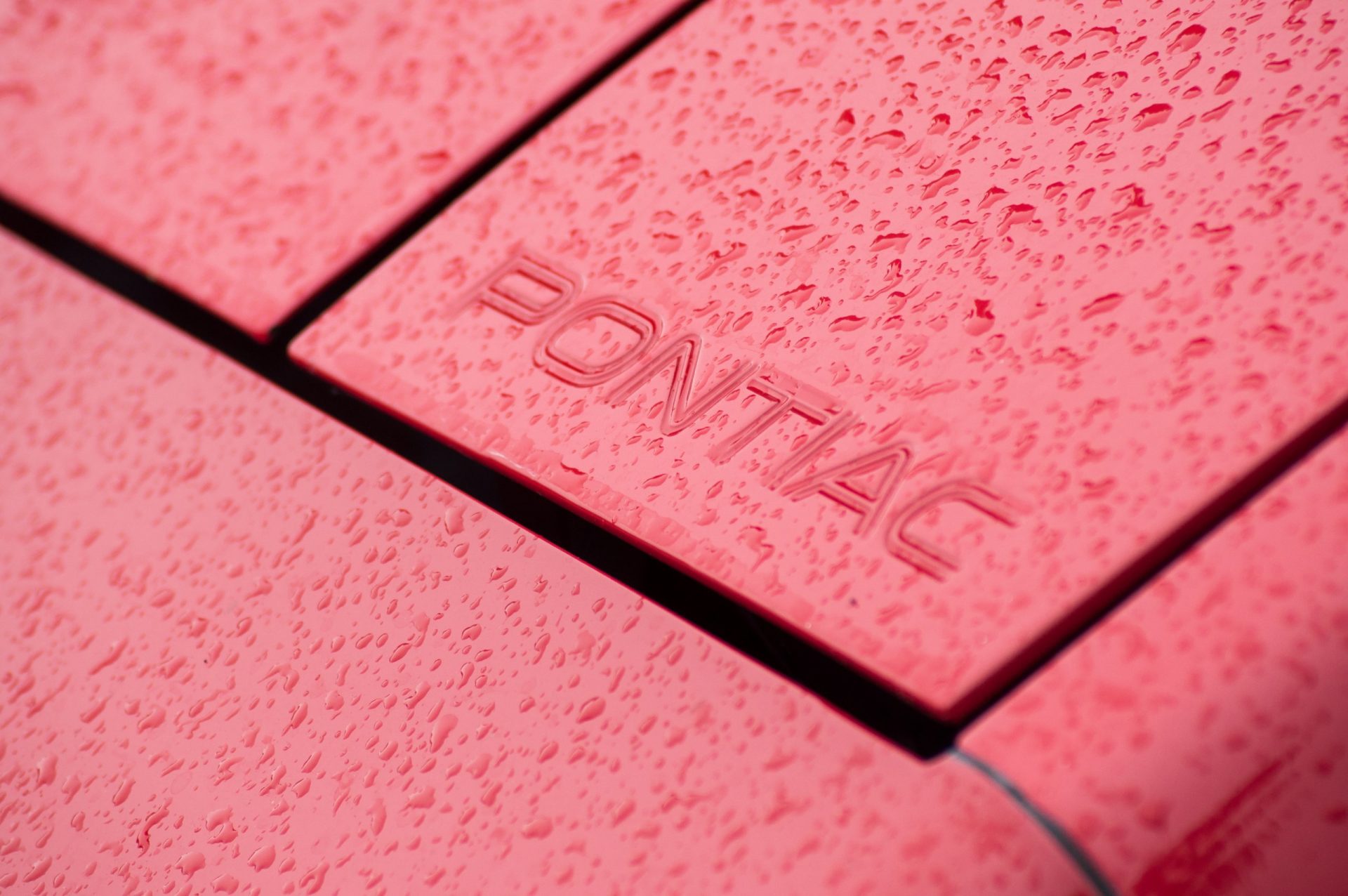  Closeup of rain drops on Pontiac logo on vintage car at fun car show event