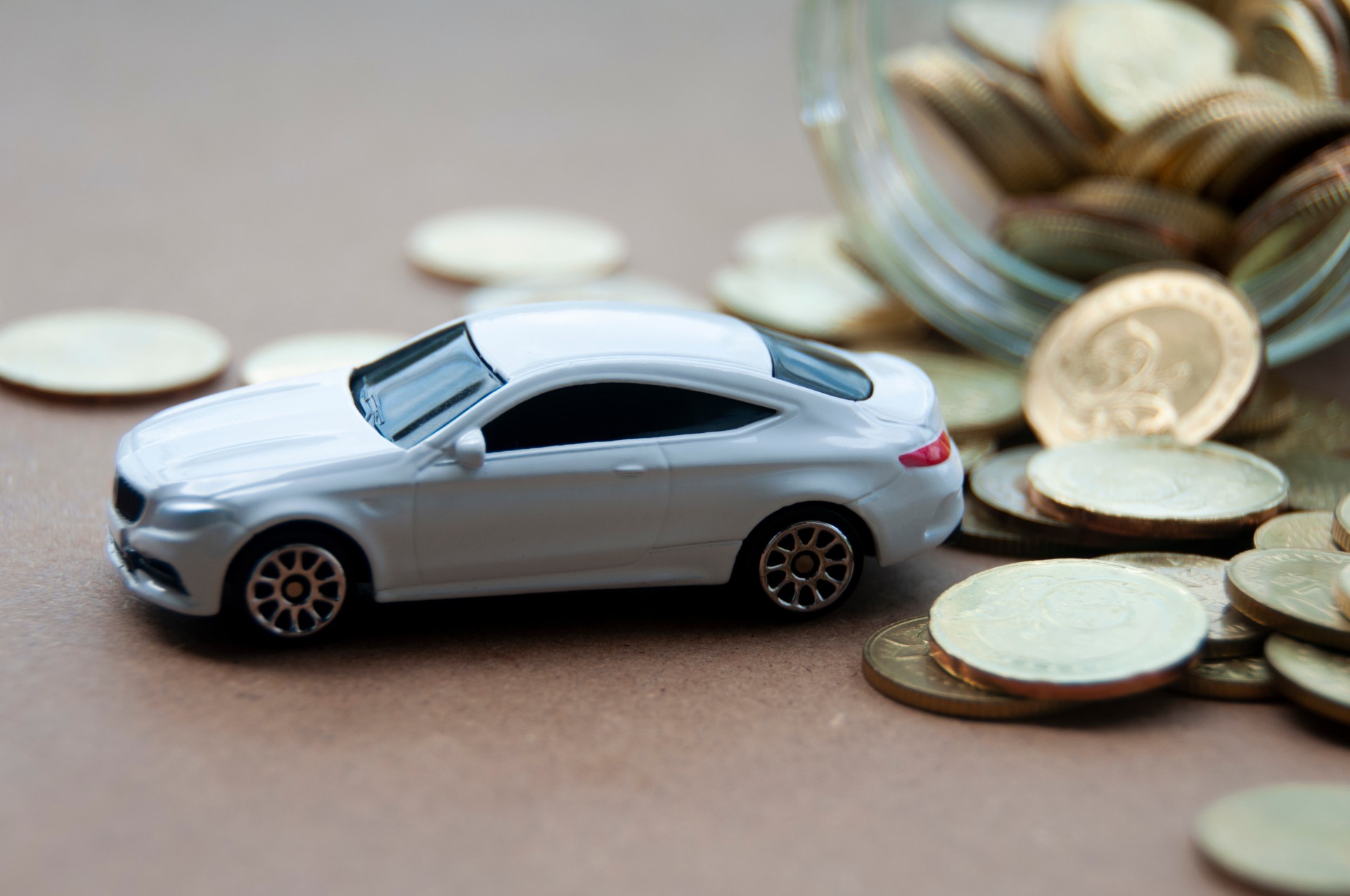Miniature toy car of Mercedes AMG with gold coin background.
