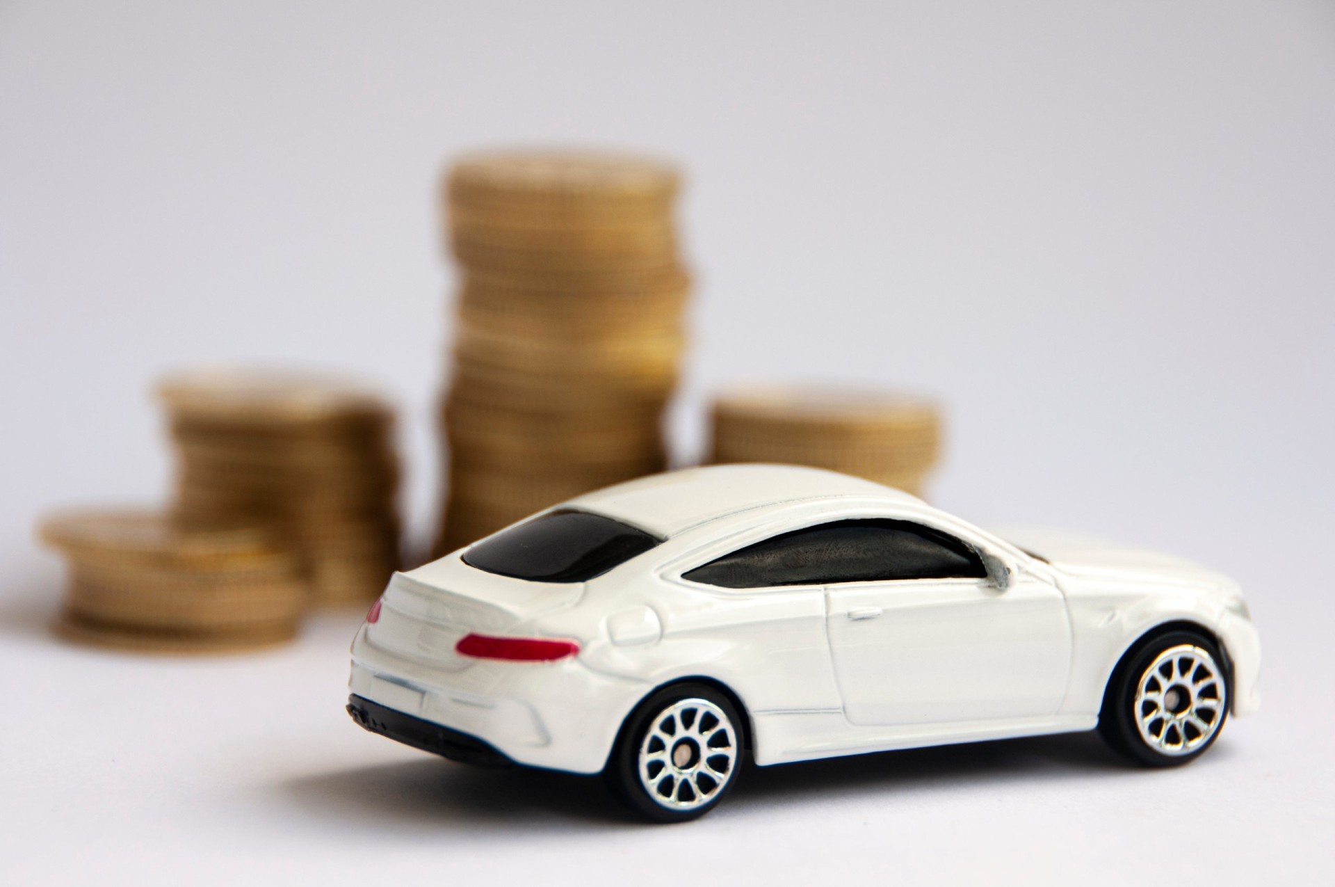Miniature toy car of Mercedes AMG with gold coin background. 