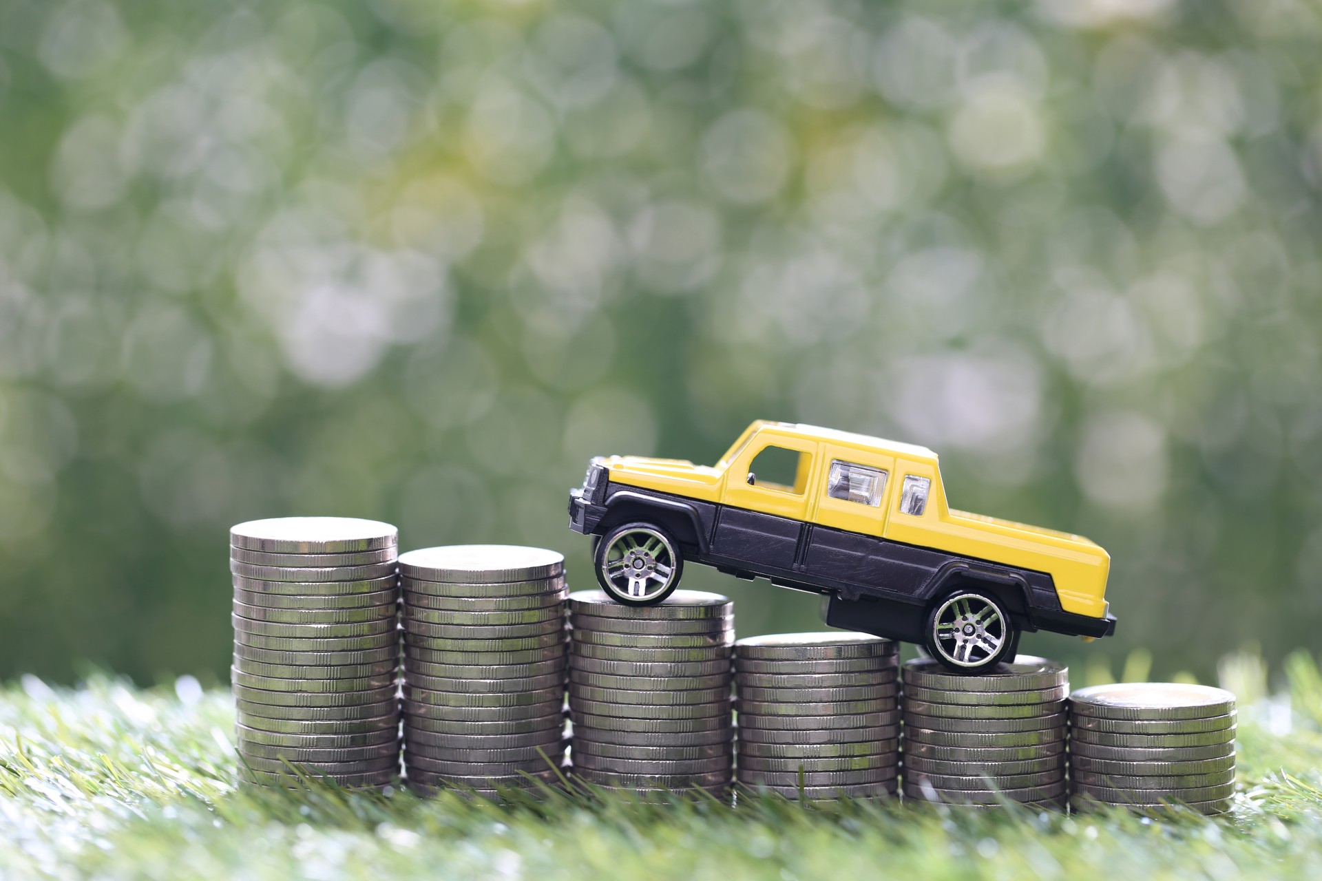 Miniature car model on growing stack of coins money on nature green background, Saving money for car, Finance and car loan, Investment and business