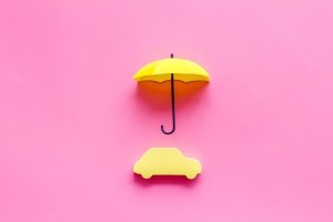 Automobile toy under umbrella on pink background top-down