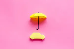Automobile toy under umbrella on pink background top-down